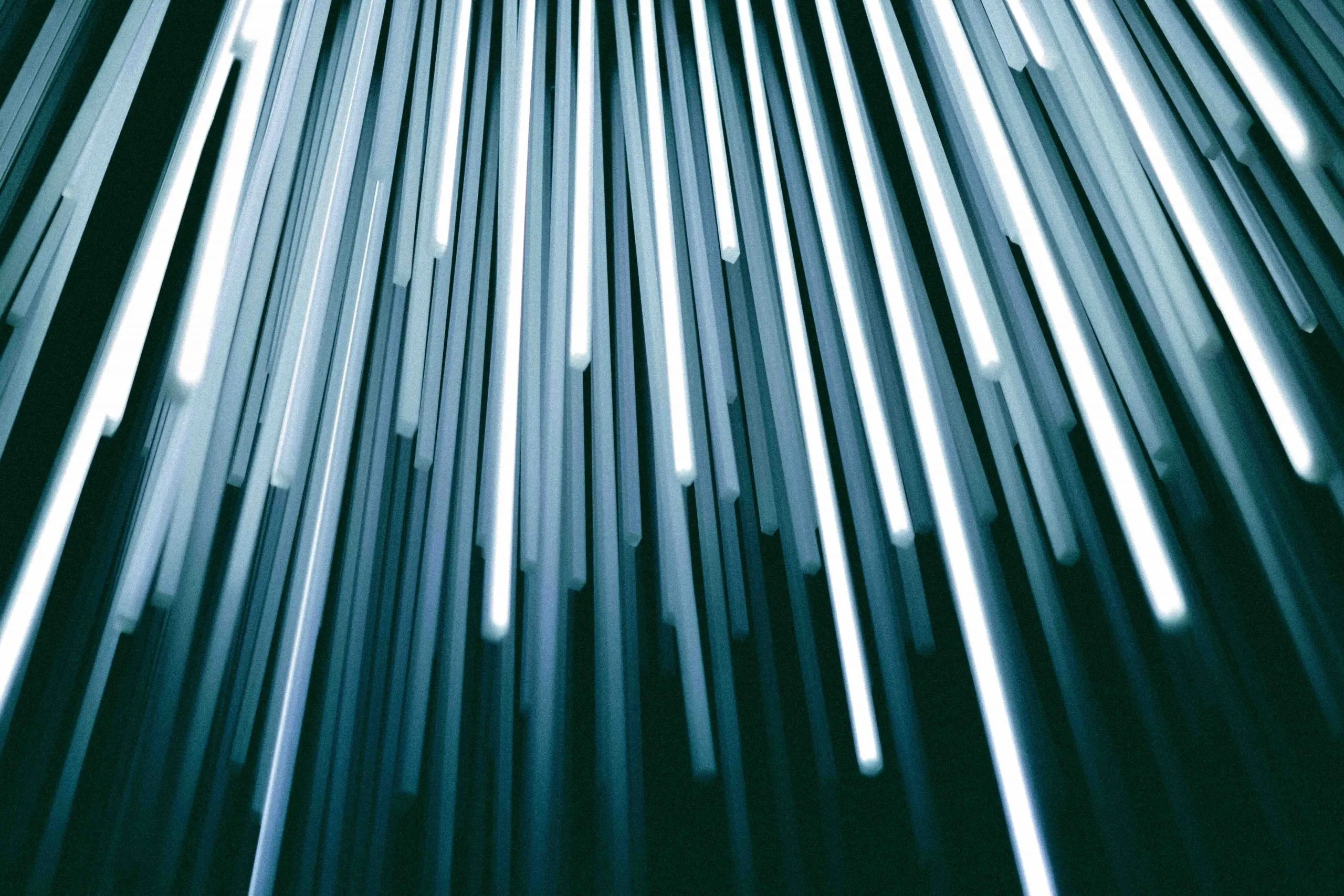Abstract field of vertical glowing blue and white light rods receding into darkness