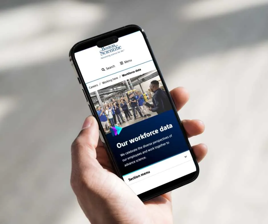 Hand holding a phone showing the Boston Scientific 'Our workforce data' page with an employees photo and intro text