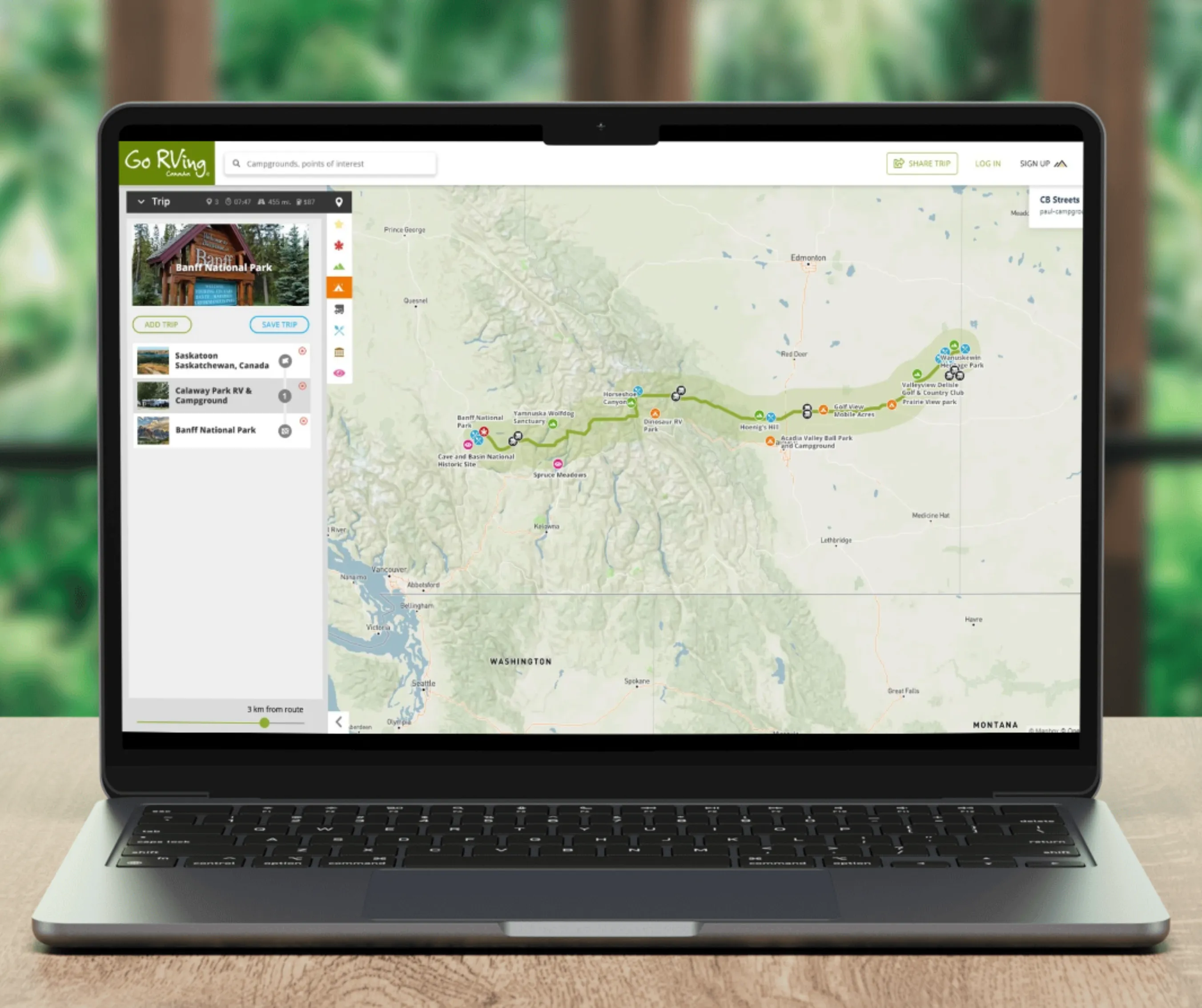 Laptop showing Go RVing trip-planner screen with a route mapped across western US and Canada and a saved-stops sidebar