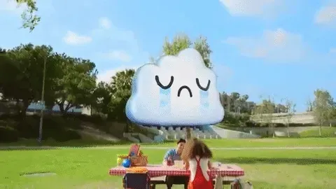 A cartoon rain cloud drizzling over a family at a park picnic table lifts away and a beaming rainbow is drawn over the scene in its place