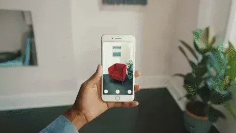 A phone and a tablet held up inside a living room, each screen showing a sofa or rug placed into the empty floor behind it