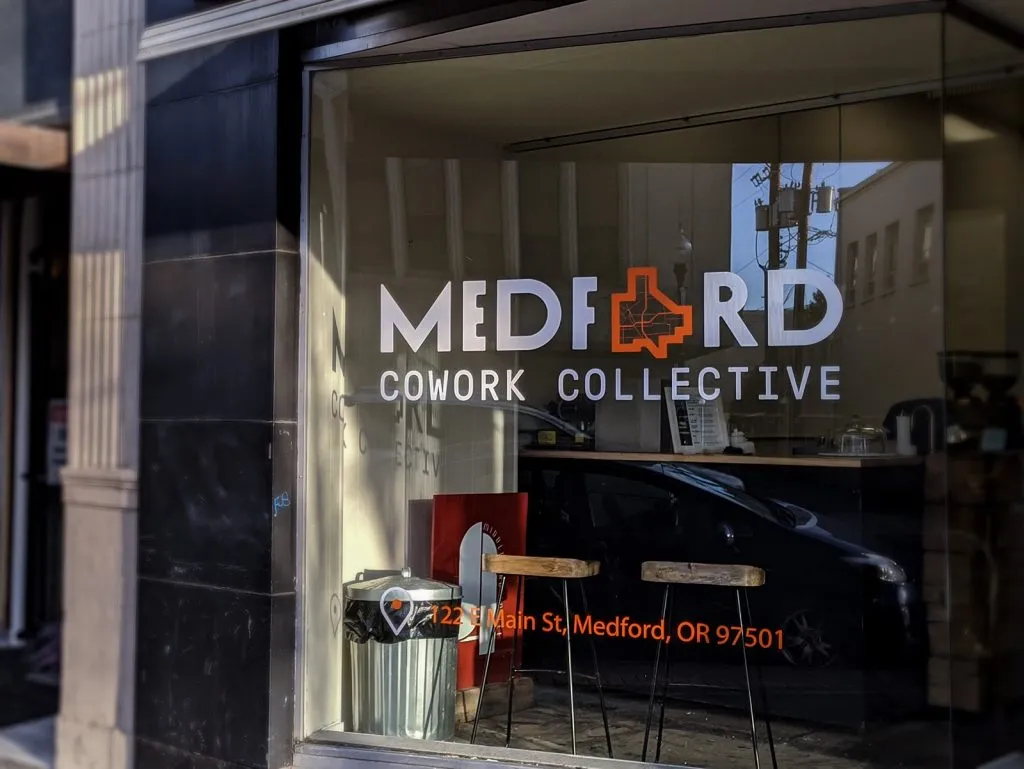 MCC storefront window with the Medford Cowork Collective logo and '122 N Main St, Medford, OR' address