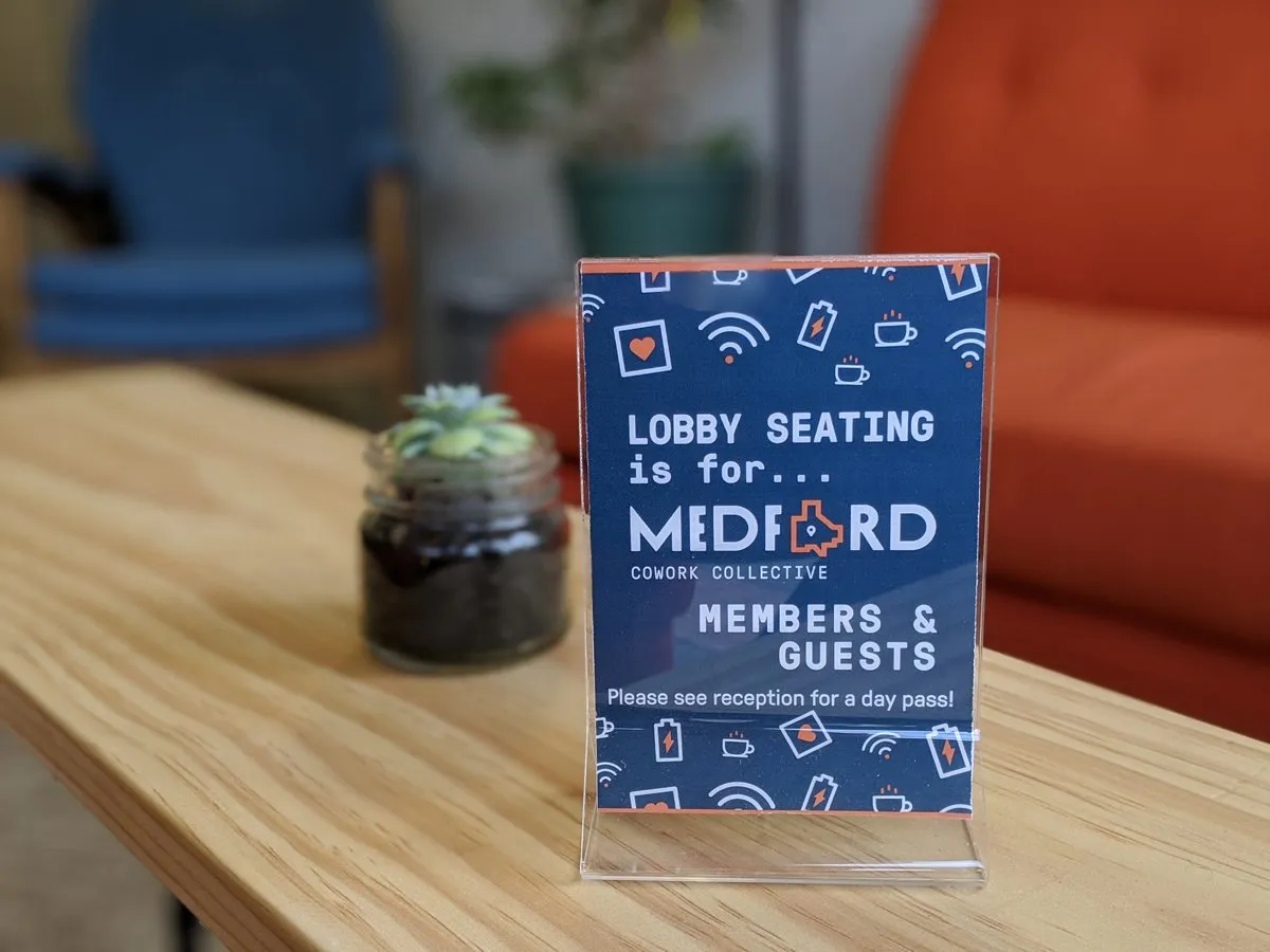Branded acrylic table sign — 'Lobby seating is for MCC members & guests' in the navy MCC icon pattern