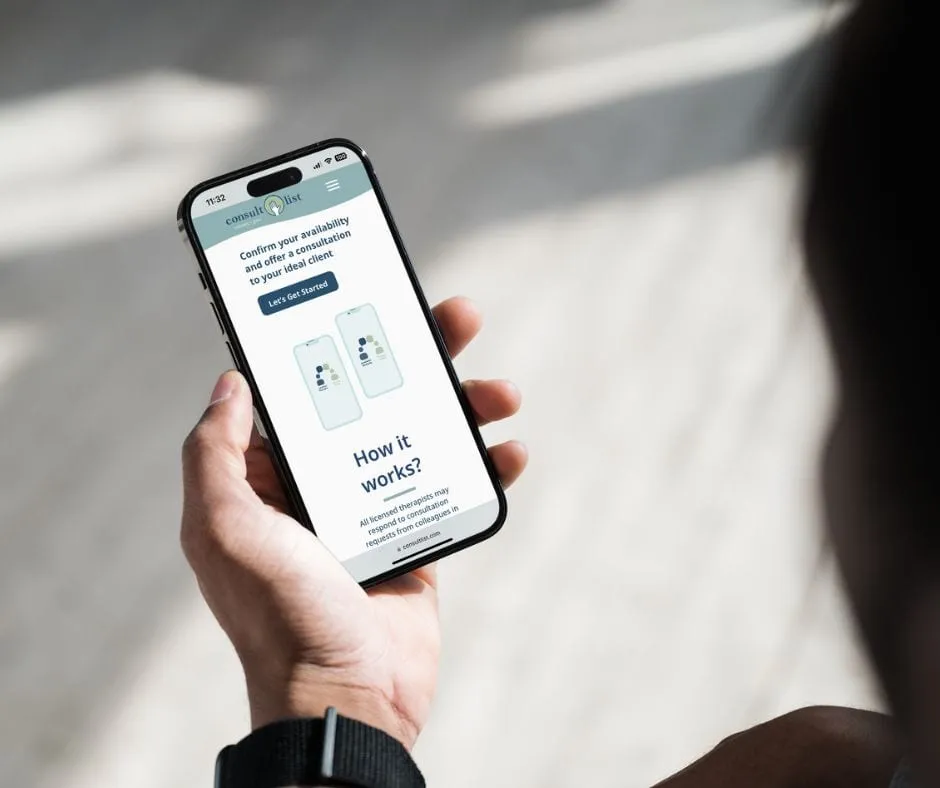An over the shoulder view of a person holding an iPhone with the consultlist.com marketing site homepage visible on the screen