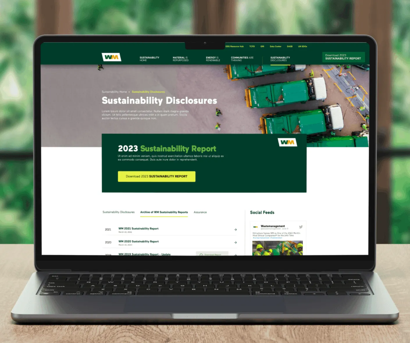 Laptop mockup of WM Sustainability Disclosures page promoting the 2023 Sustainability Report over an aerial trucks photo